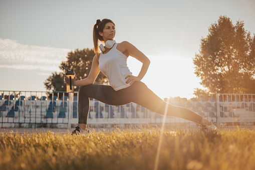 Young female athlete exercising on the track in the stadium, healthy lifestyle