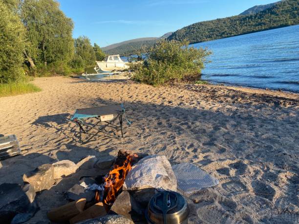 Campfire on the Beach Campfire and camping table on the beach at Kinloch Rannoch with boat moored in the Scottish Highlands beach fire scotland stock pictures, royalty-free photos & images