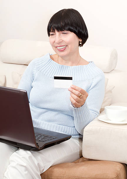 Smiling mature woman shopping online. stock photo