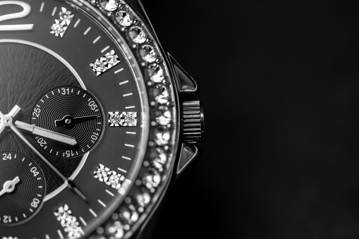 Luxury wrist watch full of diamonds on black with copy space. Analog wrist watch close up picture. Time limit.