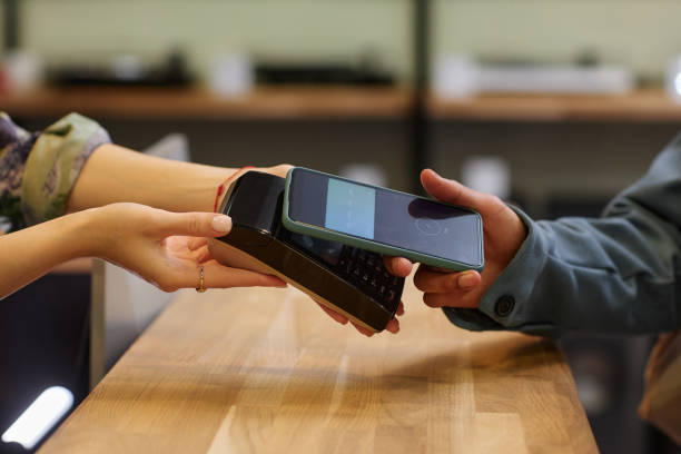 Side view closeup of young man paying with smartphone in tech store