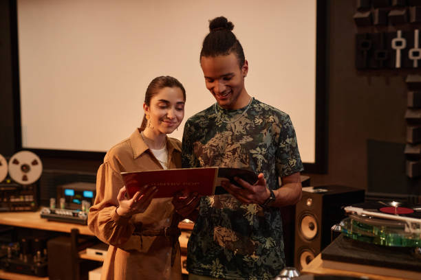 istock Young couple holding vnyl records at home studio 1550326572