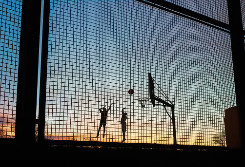 Playing basketball in the street at sunset