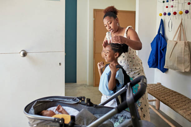 Black mother helping daughter with hair before school