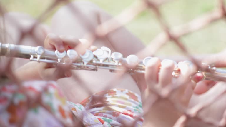 Young Girl on Swing Playing Traversal Flute