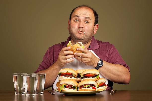 man eating many burgers - çok sayıda nesne stok fotoğraflar ve resimler