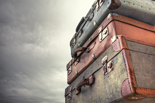 Pile of old vintage suitcases - luggage against cloudy sky. HDR image