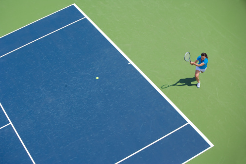 Full length aerial view of female and shadow while serving on clay tennis court. Copy space