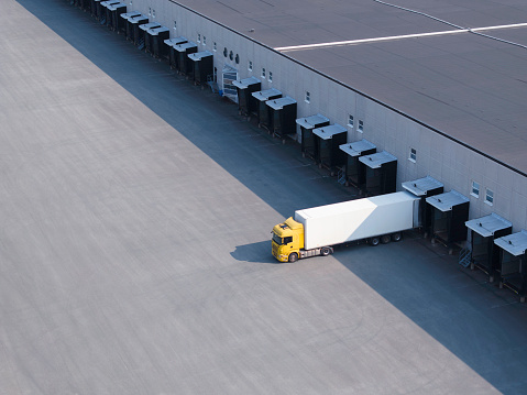 A single truck at the loading docks of a large warehouse.