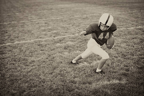 Stiff Arm A young American Football boy applies the straight arm. It is football time. Vintage theme. youth baseball and softball league photos stock pictures, royalty-free photos & images