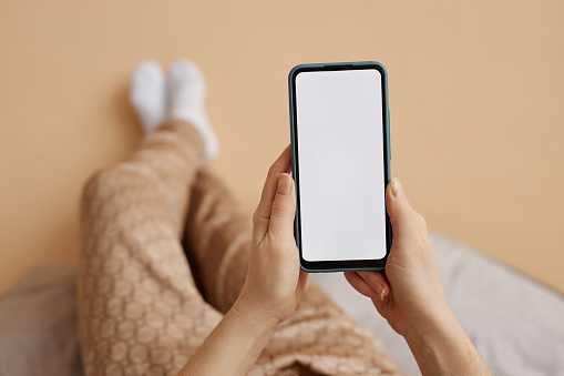 Minimal closeup of female hands holding smartphone with white screen mockup enjoying relaxing time at home, copy space