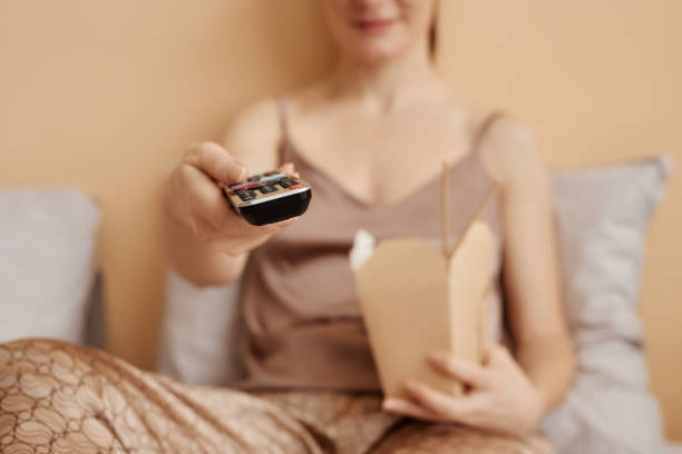 istock Young woman holding remote control enjoying relaxing weekend 1550404660