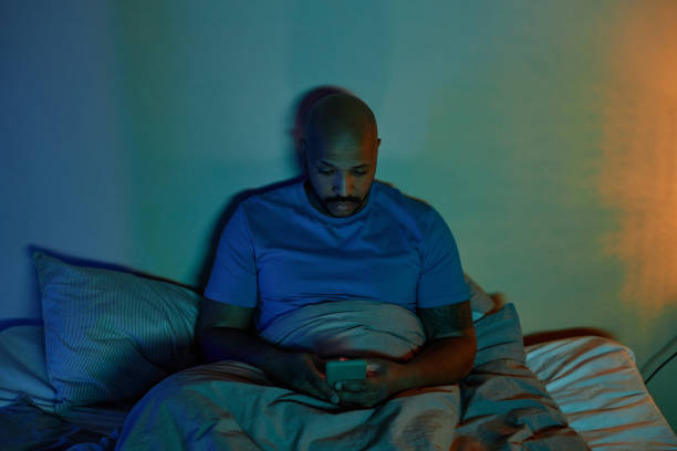 istock Black adult man using smartphone in bed at night 1550405787
