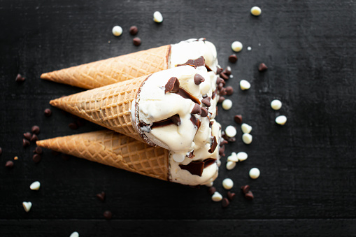 Cream ice cream cone, cream with pieces of chocolate. On a dark background