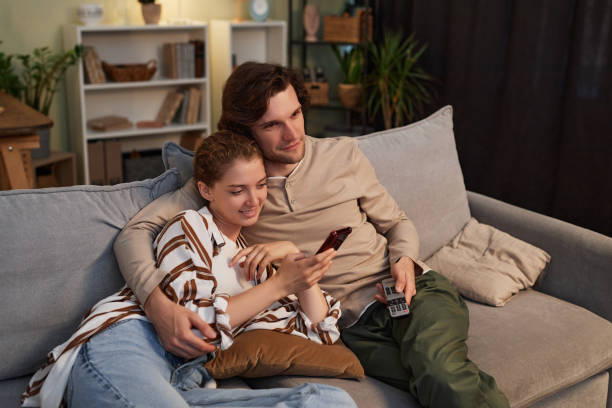 istock Couple watching TV at home together sitting on comfortable couch 1550415617