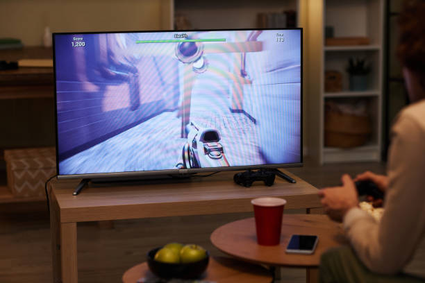 istock Man playing videogames on TV with game screen 1550415985
