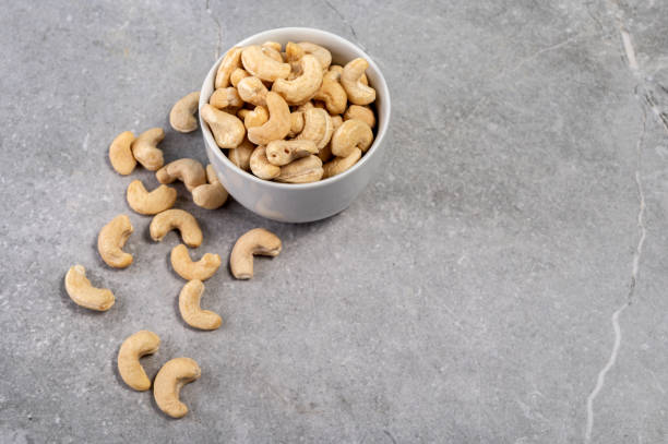 istock Cashew nuts in a white bowl, plate on a gray marble stone background 1550417839