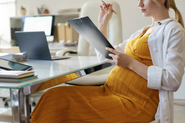 Pregnant woman filling documents in office