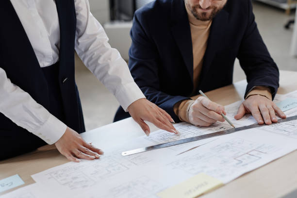 istock Two engineers at workstation drawing blueprints and plans and doing measurements 1550427655