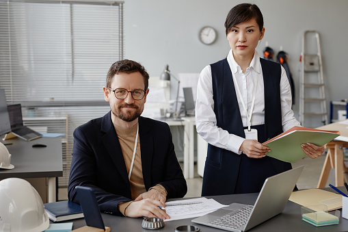 Portrait of two engineers, man and woman looking at camera in office