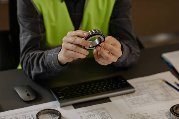 ingeniero sosteniendo piezas de máquina de rodamientos de bolas de acero diseñando automóviles en la oficina - ball bearing drawing engineer machine part fotografías e imágenes de stock