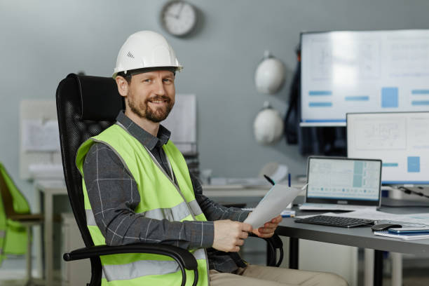 istock Smiling engineer wearing hardhat at workplace in office and looking at camera 1550428755