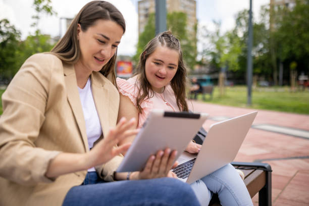 istock Two women using digital devices in a public park 1550434864