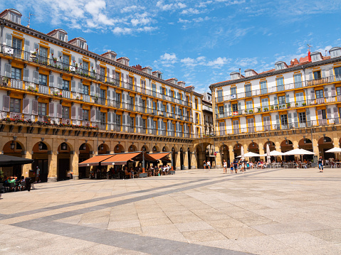 View of the Plaza de la Constitucion (Constitution Square) in heart of San Sebastian Old Town, Spain. Rectangular shape and surrounded by 4-storey arcaded buildings. Blue sky background.
