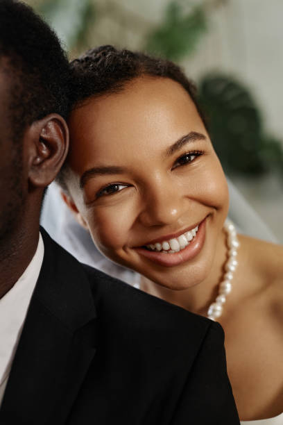 istock Closeup beautiful black bride looking at camera over husbands shoulder 1550450838