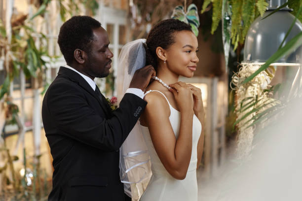 Young black couple getting married groom helping bride with necklace