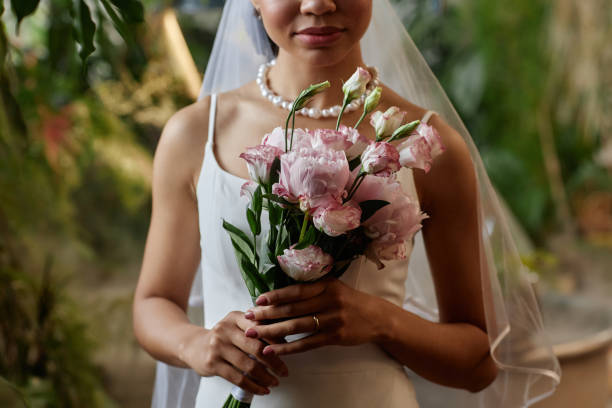 Young black woman as bride wearing wedding dress and holding flower bouquet