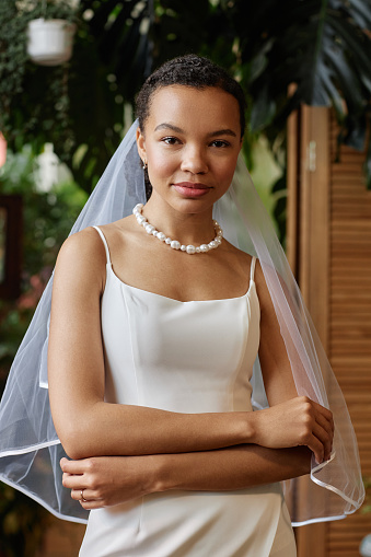 Vertical portrait of beautiful African American woman wearing wedding gown and looking at camera