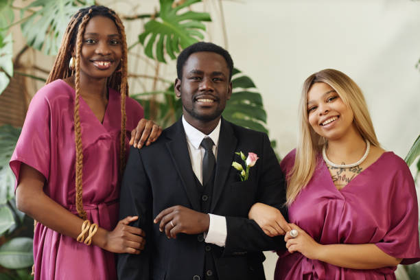 istock Smiling black man as groom posing with bridesmaids and looking at camera 1550451417