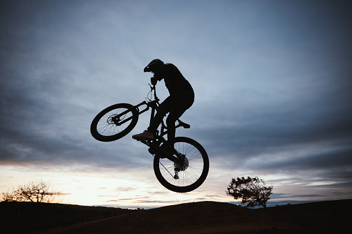 Motorcycle, sunset and jump with sport with sky or action with training in outdoor for race or risk. Adventure, silhouette and dirt bike with speed in nature with freedom or power in desert on hill.