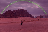 Person Walking at Wadi Rum Desert Under Geometric Neon Green Light Installation in Jordan