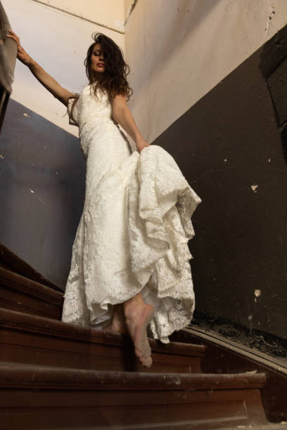 Old and dirty wooden stairs with detail of a woman,s legs wearing a wedding dress.