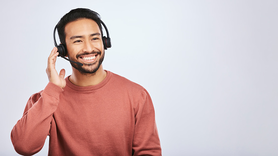 Man with headset, call center and contact us with smile, mockup space and communication on studio background. Customer service, telemarketing and tech support with male consultant and help desk job