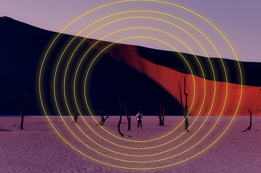 Silhouette of manat dead treee area inside of Bright neon circles at dramatic martian landscape in Namib-Naukluft National park, Namibia - Metaverse, Web3 inspiration