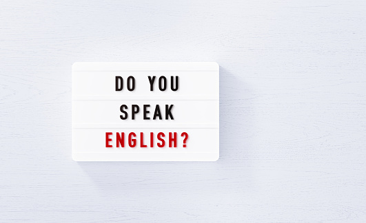 Do you speak English written white lightbox on white wood background. Horizontal composition with copy space.