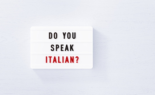 Do you speak Italian written white lightbox on white wood background. Horizontal composition with copy space.