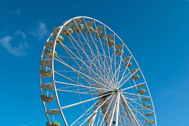 Ferris wheel against the blue sky with white clouds. Children's amusement
