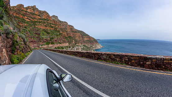 Driving on narrow road pass overlooking scenic Atlantic ocean sea water  mountain landscape on Chapmans Peak Drive route Cape Town.