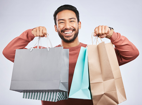 Shopping bag, studio portrait and happy man customer or client with retail product, gift or fashion spree choice. Boutique discount deal, market present and excited person smile on white background