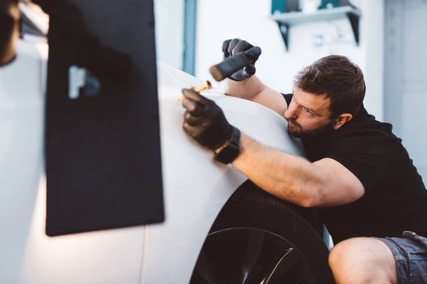 istock Car mechanic working to remove dent in workshop. 1550531783