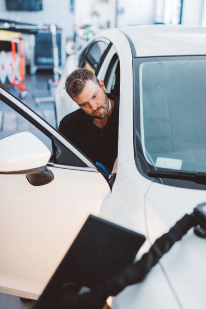 istock Car mechanic working to remove dent in workshop. 1550531788