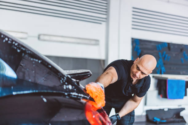 istock Service man washing car before detailing in workshop. 1550531876