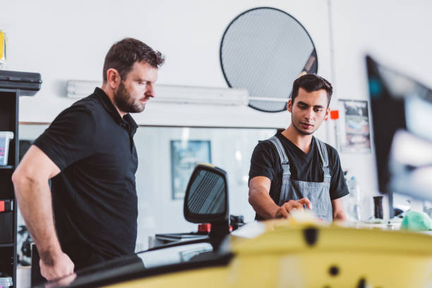 istock Car mechanics working to remove dent in workshop. 1550532335