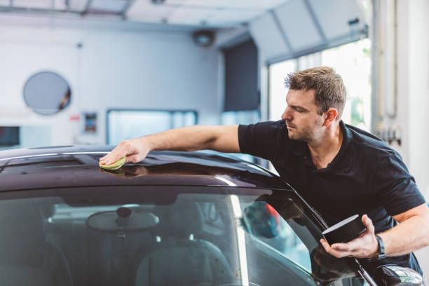 istock Service man applying wax or coating on car in detailing workshop 1550532394