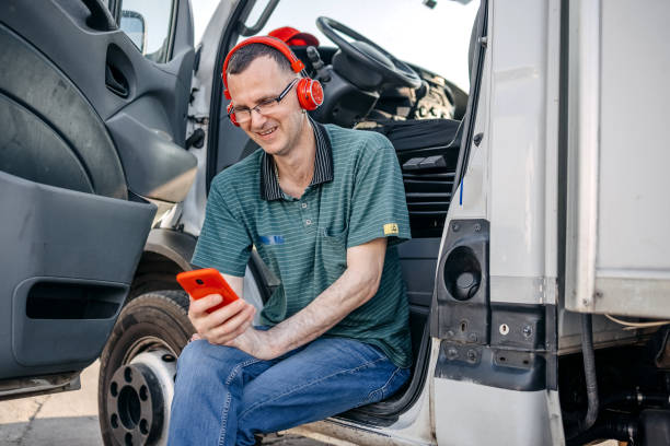 man working in delivery service using delivery van and wearing wireless headphones on his head - delivery van audio imagens e fotografias de stock