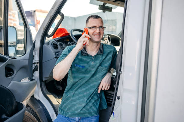 istock Man working in delivery service using delivery van and having a call on his mobile phone 1550541793